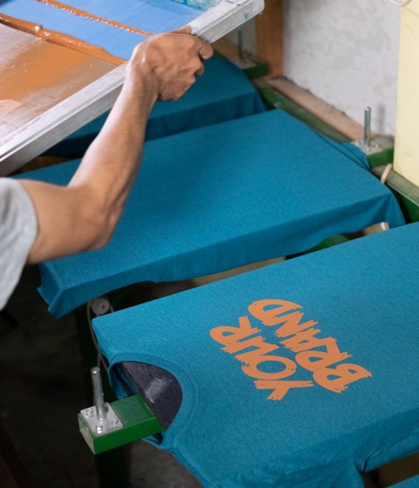 close up of male workers hold and lift the screen printing frames after printing the t-shirts at the workshop